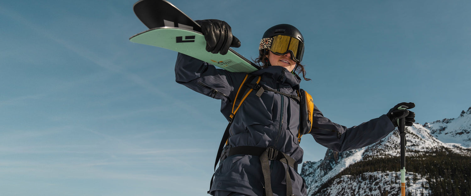 A skier carrying her skis against a blue sky background